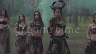 穿着森林居民或魔鬼的戏剧服装的年轻妇女在迷人的森林中表现出芬芳和跳舞的肚皮